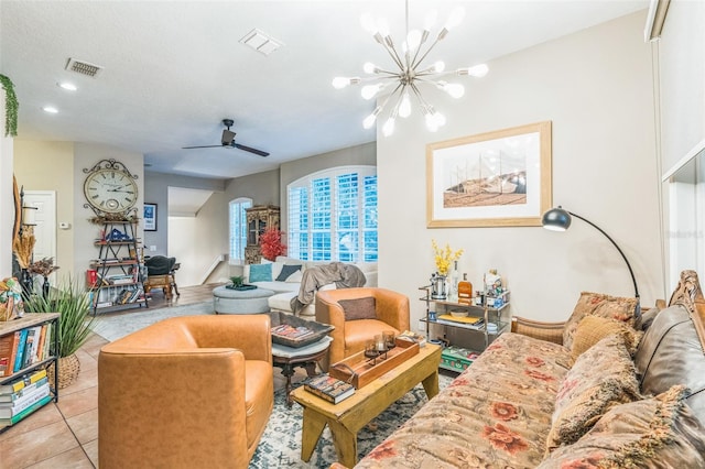 tiled living room with ceiling fan with notable chandelier