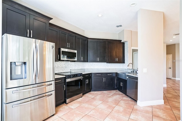 kitchen with visible vents, light tile patterned flooring, a sink, stainless steel appliances, and backsplash