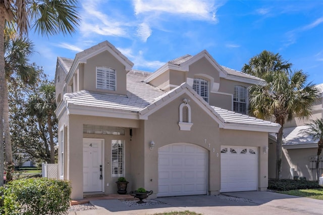 view of front facade featuring stucco siding, concrete driveway, a tile roof, and a garage