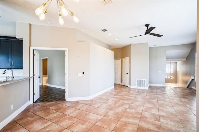 unfurnished living room with a sink, visible vents, ceiling fan with notable chandelier, and light tile patterned floors