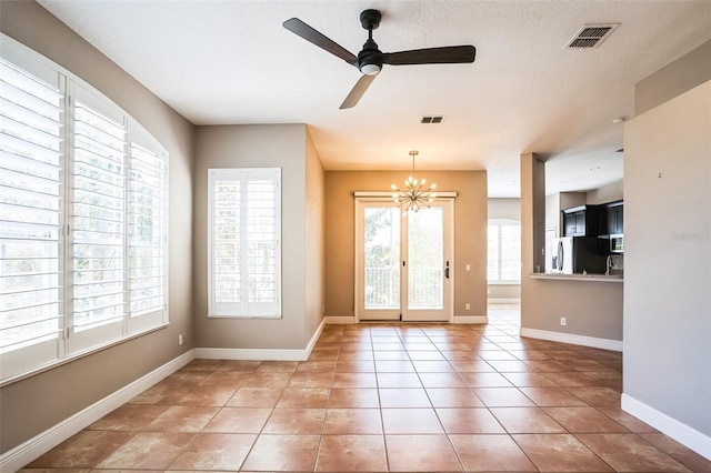 interior space with light tile patterned floors, visible vents, baseboards, and ceiling fan with notable chandelier