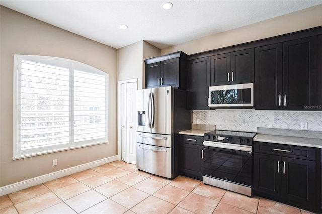 kitchen featuring decorative backsplash, light countertops, dark cabinets, and appliances with stainless steel finishes