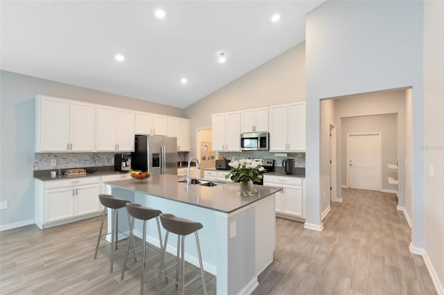 kitchen with a center island with sink, sink, light hardwood / wood-style flooring, appliances with stainless steel finishes, and a breakfast bar area