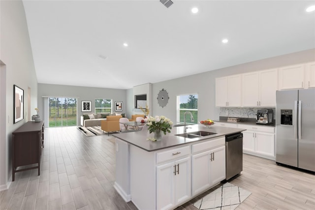 kitchen with sink, an island with sink, light hardwood / wood-style floors, white cabinetry, and stainless steel appliances