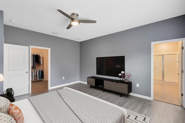 bedroom with a spacious closet, a closet, ceiling fan, and hardwood / wood-style flooring