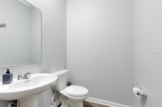 bathroom with wood-type flooring, toilet, and sink