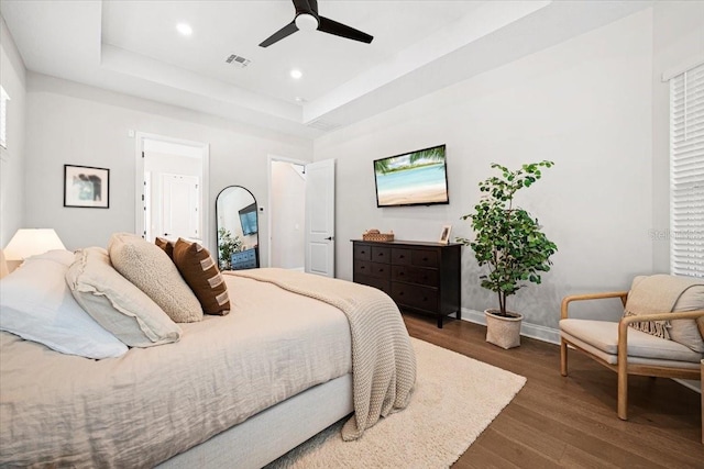 bedroom featuring a tray ceiling, ceiling fan, and dark wood-type flooring