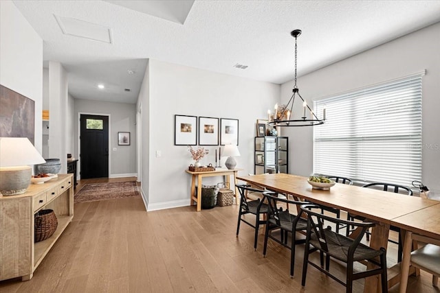 dining space with a chandelier, a textured ceiling, and light hardwood / wood-style flooring