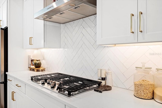 kitchen featuring tasteful backsplash, light stone counters, white cabinetry, stainless steel appliances, and extractor fan