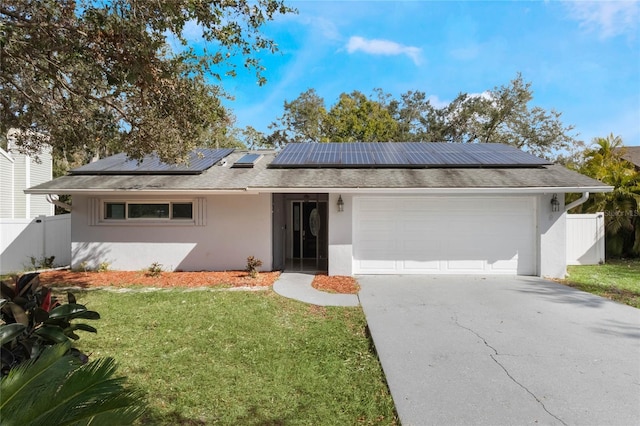 ranch-style home with solar panels, a garage, and a front lawn