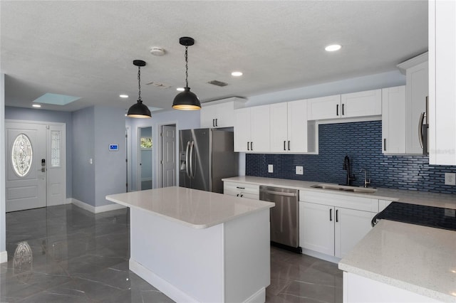 kitchen with sink, a center island, hanging light fixtures, white cabinets, and appliances with stainless steel finishes