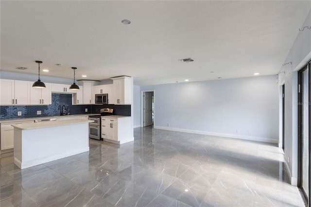 kitchen featuring backsplash, stainless steel appliances, a center island, white cabinetry, and hanging light fixtures