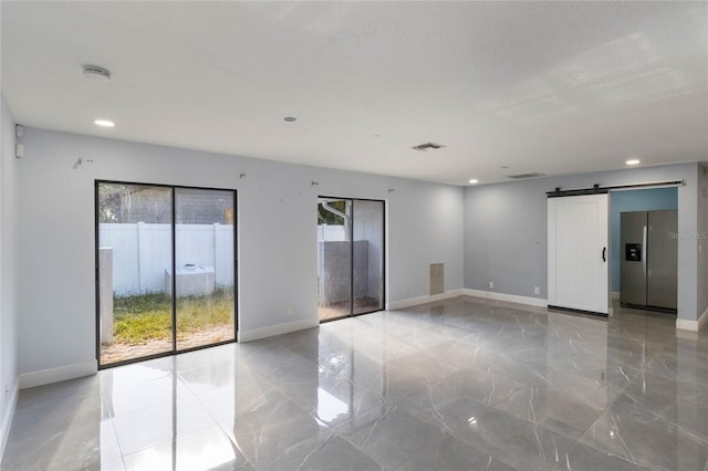 spare room with a barn door and a wealth of natural light