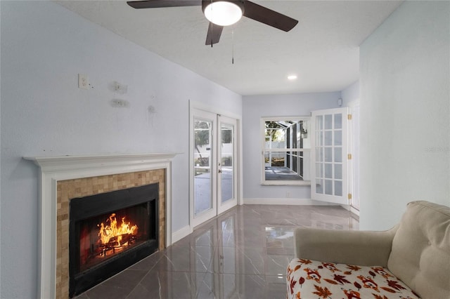 unfurnished living room featuring a tiled fireplace, ceiling fan, and french doors