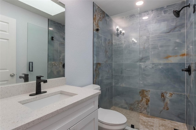 bathroom featuring vanity, toilet, and a tile shower