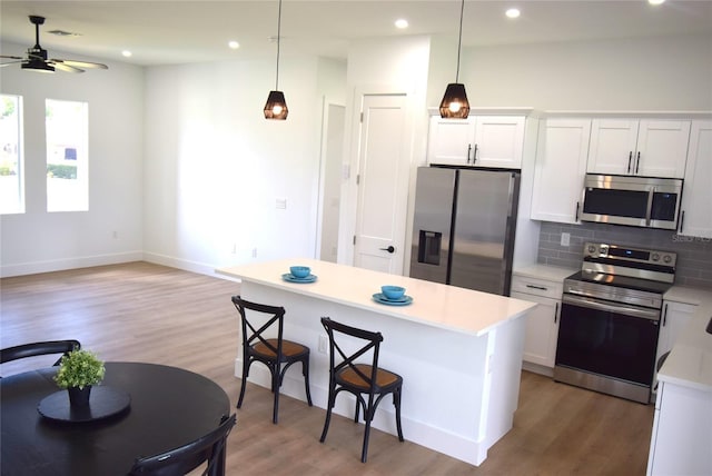 kitchen featuring white cabinets, stainless steel appliances, tasteful backsplash, and ceiling fan