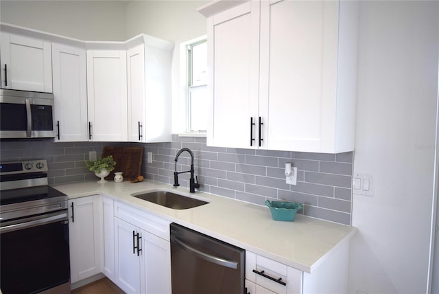 kitchen with white cabinets, appliances with stainless steel finishes, decorative backsplash, and sink