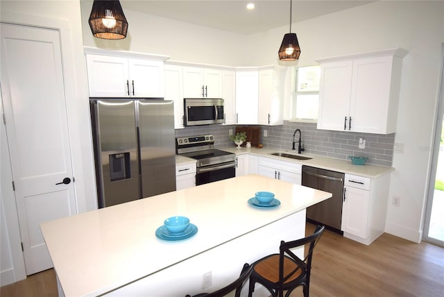 kitchen with white cabinetry, sink, a center island, hardwood / wood-style floors, and appliances with stainless steel finishes