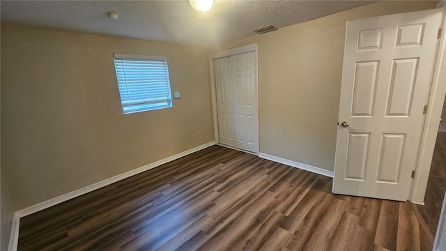 unfurnished bedroom featuring a closet, dark hardwood / wood-style flooring, and a textured ceiling