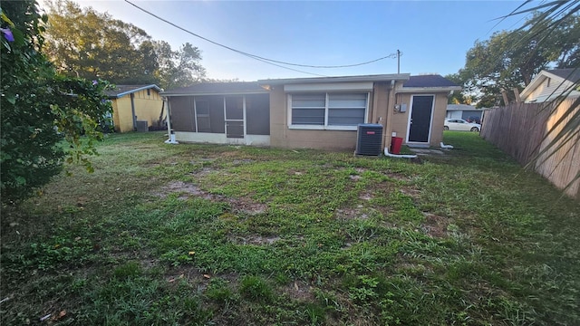 back of property featuring central AC and a lawn