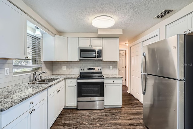 kitchen featuring sink, white cabinets, stainless steel appliances, light stone countertops, and dark wood-type flooring