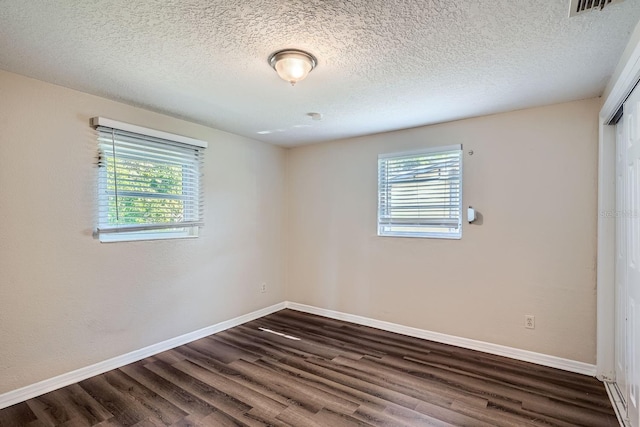 unfurnished room with dark hardwood / wood-style flooring and a textured ceiling