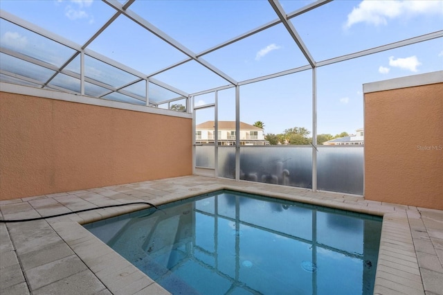 view of swimming pool featuring glass enclosure and a patio area