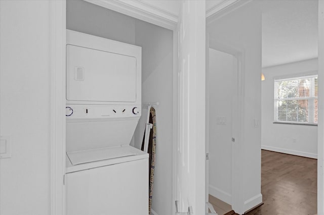 laundry area with stacked washer / drying machine and dark hardwood / wood-style flooring