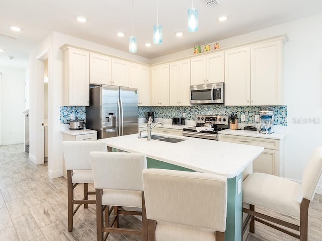 kitchen featuring a sink, light countertops, appliances with stainless steel finishes, hanging light fixtures, and decorative backsplash