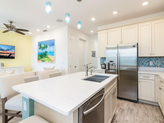 kitchen featuring tasteful backsplash, visible vents, appliances with stainless steel finishes, open floor plan, and a sink