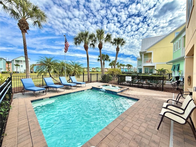 view of swimming pool featuring a patio area, a pool with connected hot tub, and fence