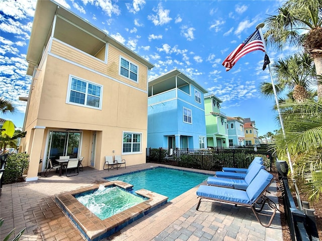 view of pool with a pool with connected hot tub, a patio area, and fence