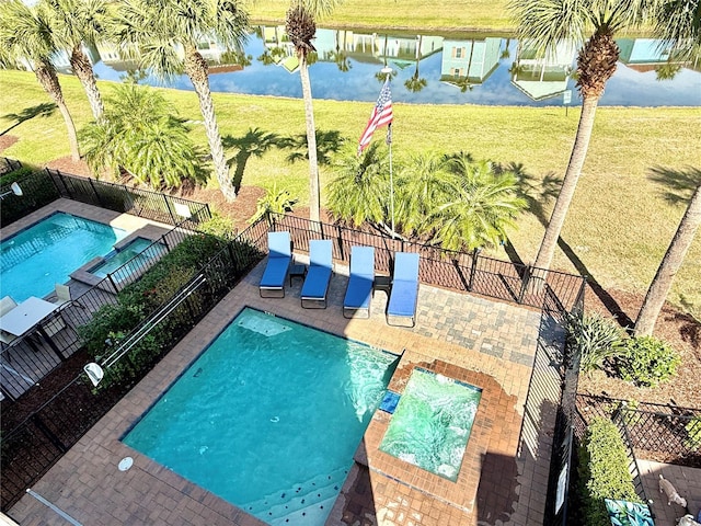 view of swimming pool with a pool with connected hot tub, a water view, a patio, and fence