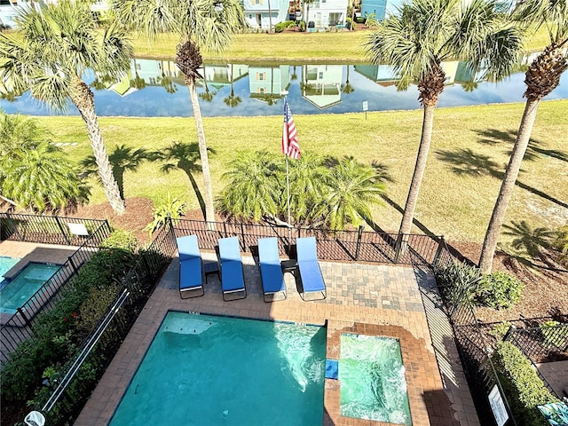 community pool featuring a patio, a yard, a water view, and a fenced backyard