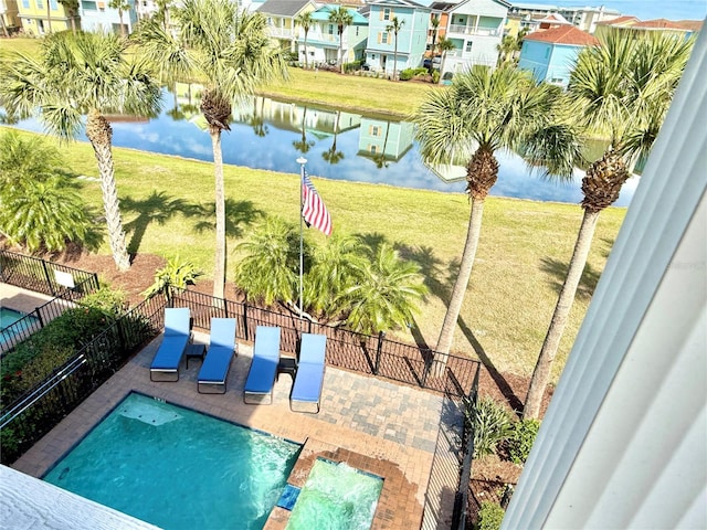 view of pool featuring a patio, a water view, a lawn, fence, and a residential view