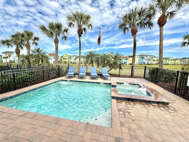 community pool with a patio area, a hot tub, a residential view, and fence