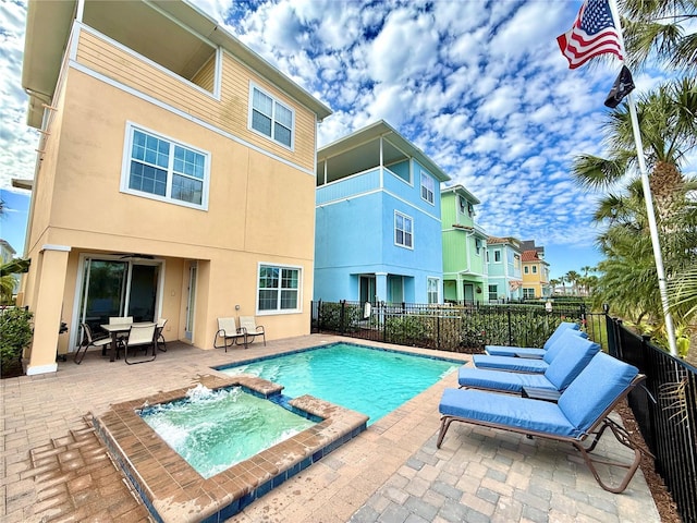 view of swimming pool featuring a pool with connected hot tub, a patio area, and fence