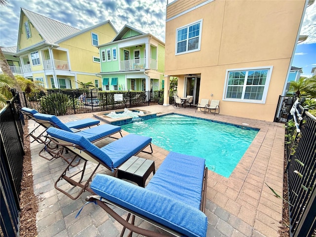 view of pool with a pool with connected hot tub, a patio area, and fence