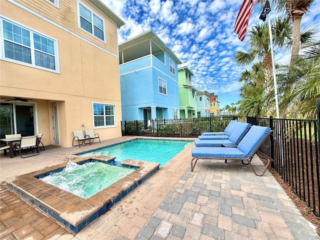 view of swimming pool with a pool with connected hot tub, a patio area, and fence