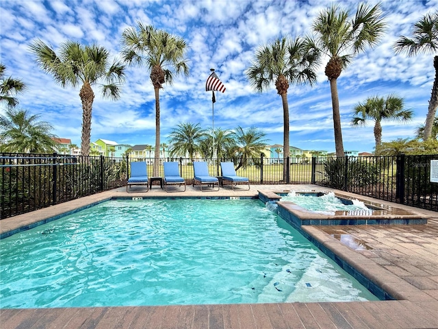 view of pool with a patio area, fence, and a pool with connected hot tub