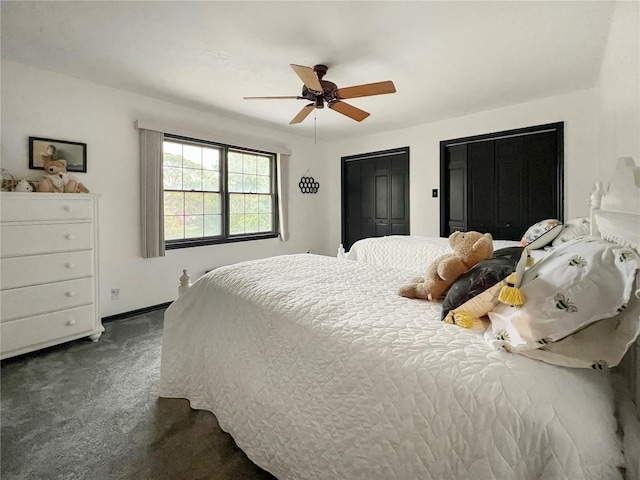 bedroom with dark colored carpet, two closets, and ceiling fan