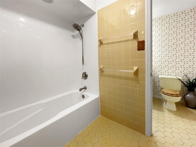 bathroom with tile patterned flooring, tiled shower / bath combo, and toilet