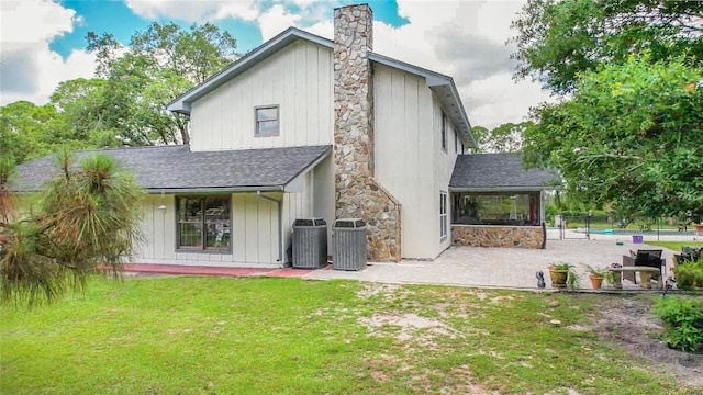 6885 Orchid Tree Dr, Grant, FL 32949 - back of house featuring roof with shingles, a patio, central AC, a chimney, and board and batten siding