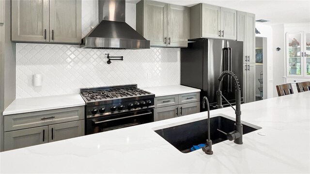 6885 Orchid Tree Dr, Grant, FL 32949 - kitchen with wall chimney exhaust hood, high end range, freestanding refrigerator, gray cabinets, and a sink
