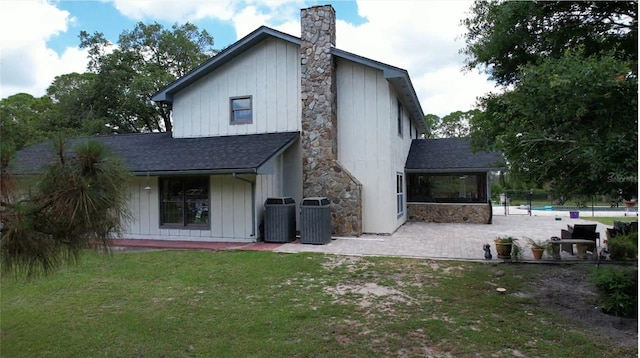 6885 Orchid Tree Dr, Grant, FL 32949 - rear view of property with a shingled roof, a patio, a chimney, central AC unit, and board and batten siding