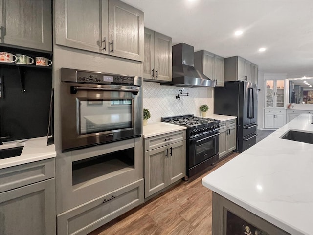 6885 Orchid Tree Dr, Grant, FL 32949 - kitchen with wall chimney range hood, stainless steel appliances, gray cabinetry, decorative backsplash, and a sink