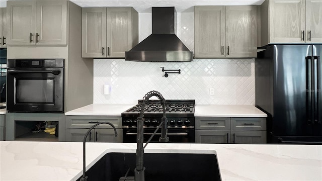 6885 Orchid Tree Dr, Grant, FL 32949 - kitchen with wall chimney exhaust hood, black appliances, gray cabinets, and backsplash