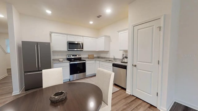 kitchen with light hardwood / wood-style floors, white cabinetry, sink, and appliances with stainless steel finishes