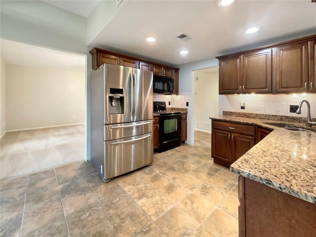 kitchen with light stone countertops, sink, tasteful backsplash, and black appliances