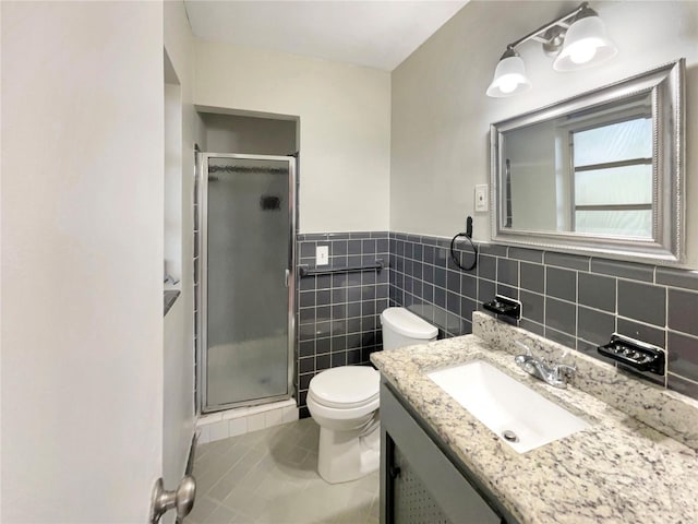 bathroom with vanity, tile patterned flooring, toilet, tile walls, and a shower with shower door